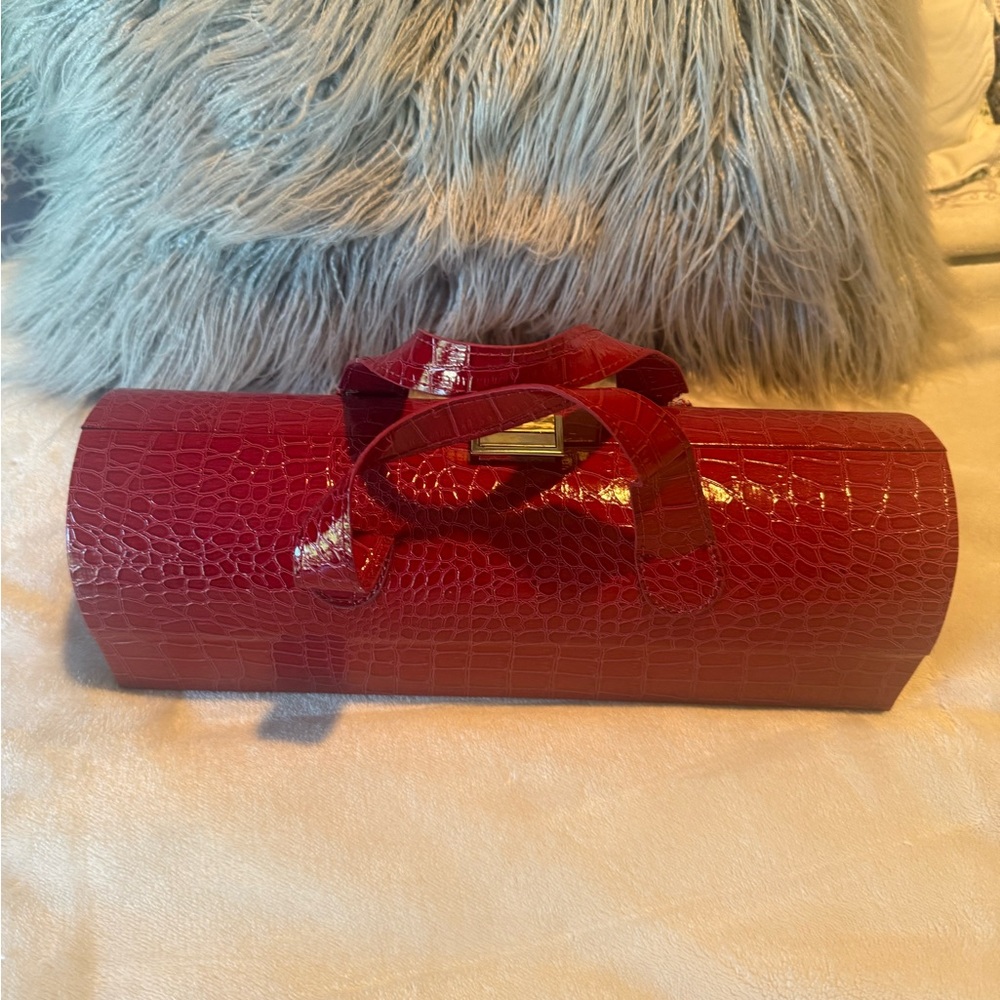 Red patent wine bottle carrier with pocket for wine opener.